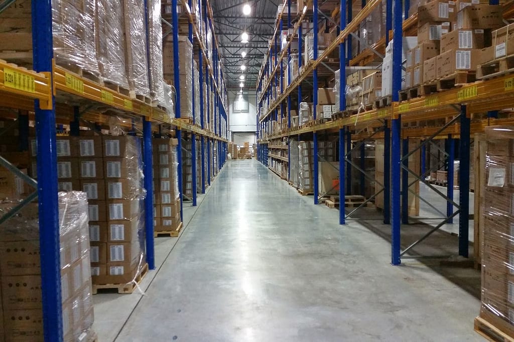 Corredor de armazém com estantes cheias de paletes