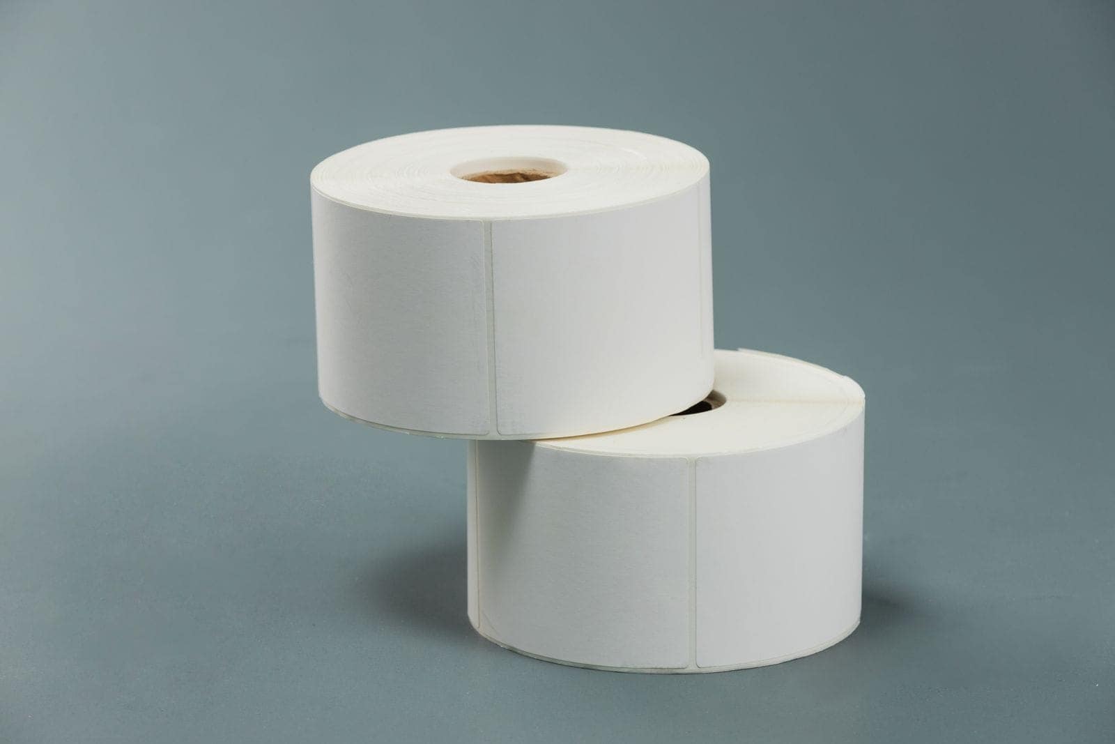 Dois rolos de papel branco empilhados sobre fundo cinzento