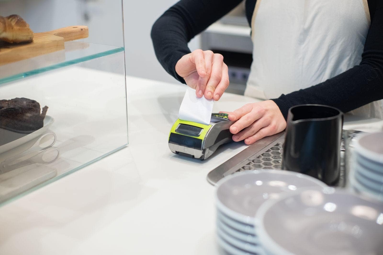 Funcionária de um café a destacar o talão do terminal no balcão